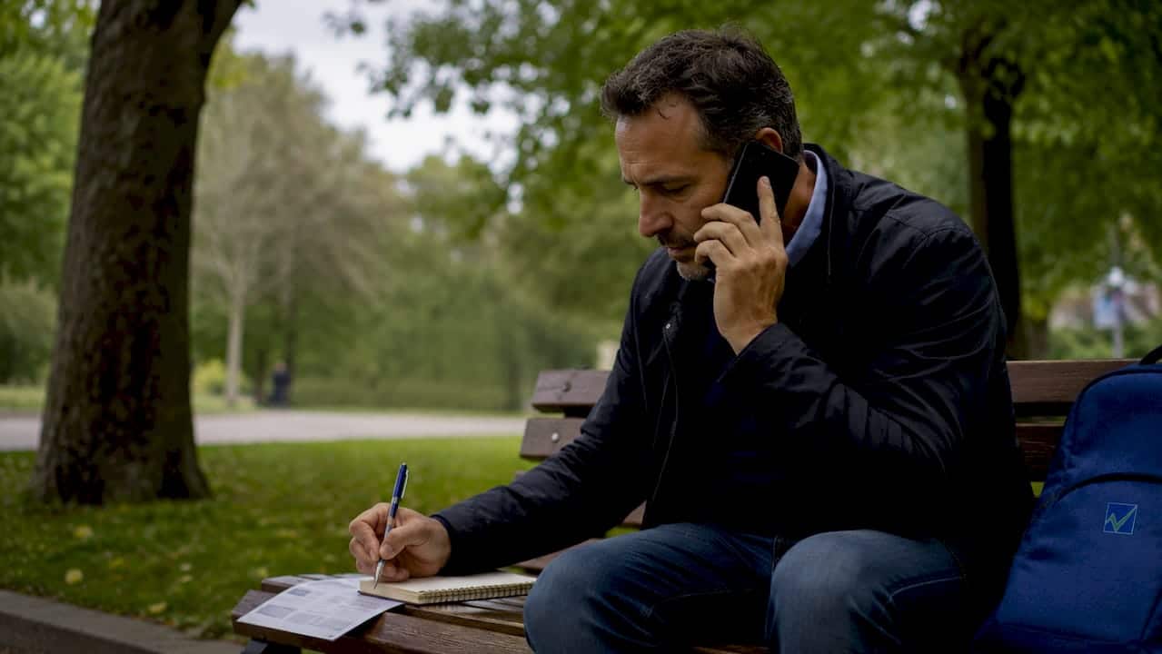 Persona seduta a un tavolo mentre compila i moduli per la voltura della fornitura elettrica