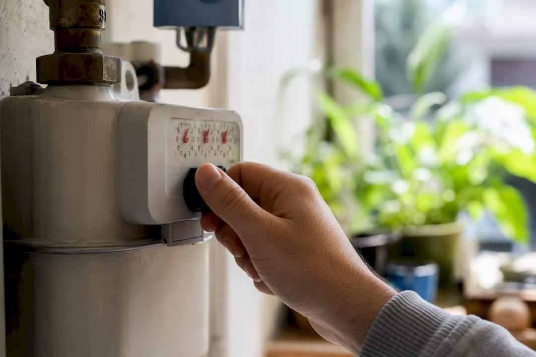 Primo piano di una mano che regola la manopola del contatore del gas