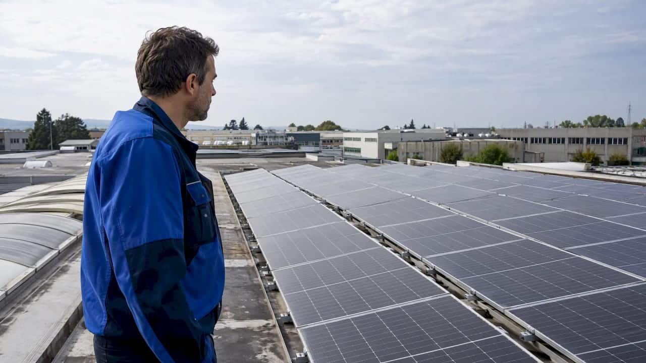 Tecnico che esamina i pannelli fotovoltaici sul tetto dell'azienda